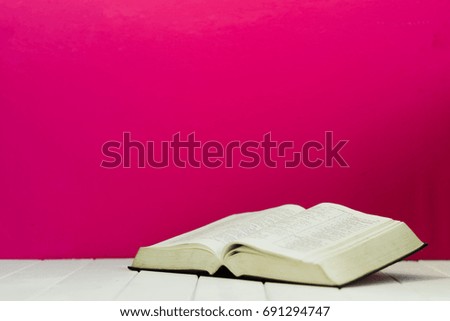 Bible and the crucifix on a white wooden table. Beautiful pink background.Religion concept