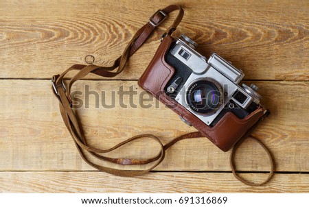 Old retro camera on vintage rustic wooden planks boards. Education photography courses back to  school concept abstract background. Close up, top view, copy space.
