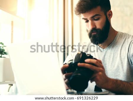 Portrait of young man photographer checking previews on camera in the studio.