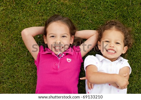 Cute little sisters laying in grass
