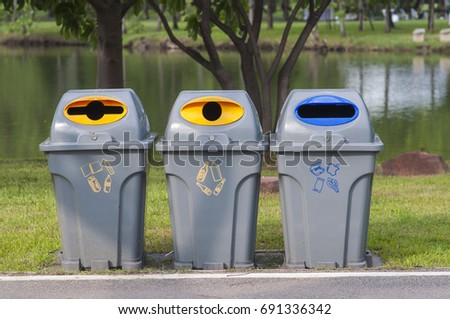 Color trash containers for separate garbage. Trash bin along the way in park. Garbage separate bin in park. Royalty-Free Stock Photo #691336342