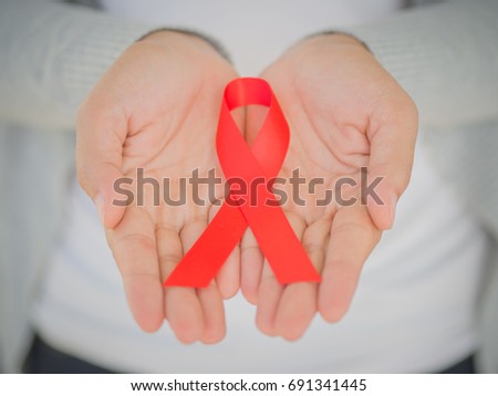 Closeup woman hands holding red ribbon HIV, world AIDS day awareness ribbon.  Healthcare and medicine concept. awareness ribbon.  Healthcare and medicine concept.