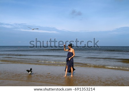  Baltic sea,  woman walking along the beach and feeding black crows