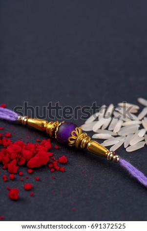 Raksha Bandhan : Rakhi with rice grains and kumkum on black background, Traditional Indian wrist band which is a symbol of love between Brothers and Sisters.