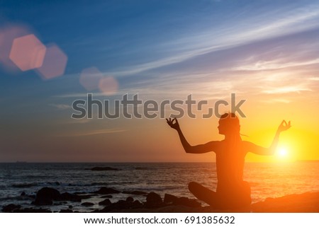Yoga silhouette. Meditation woman on the ocean during amazing sunset. Healthy lifestyle. 