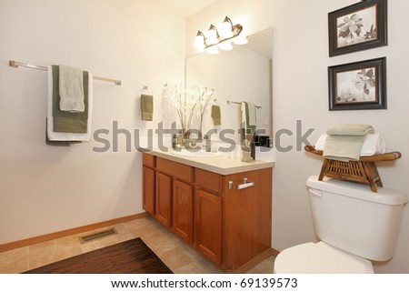 Cherry cabinet and yellow curtains in bathroom with art.