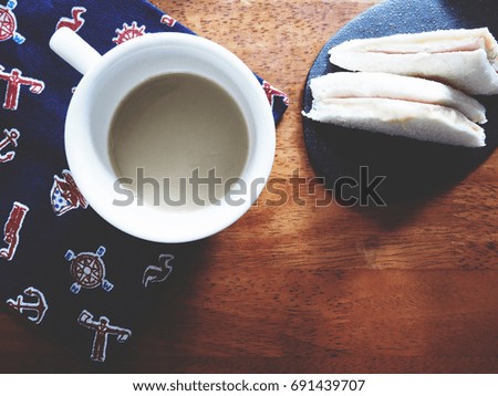 Top view picture of hot latte with ham and cheese sandwich on napkin above old  wooden table.