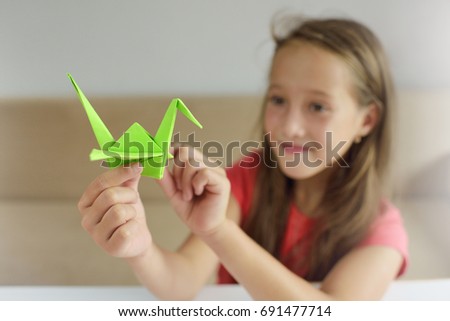 The girl puts origami from paper. Lesson of origami Royalty-Free Stock Photo #691477714
