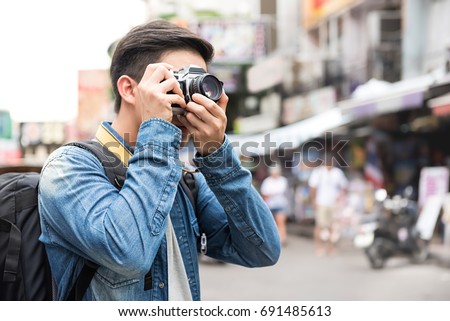 Traveling Asian male tourist backpackers taking photo in Khao san road,  Bangkok, Thailand on holidays
