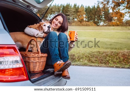 Woman with her dog have a tea time during their autumn auto travel Royalty-Free Stock Photo #691509511
