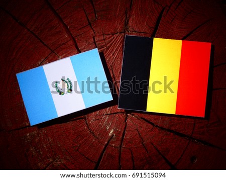 Guatemalan flag with Belgian flag on a tree stump isolated
