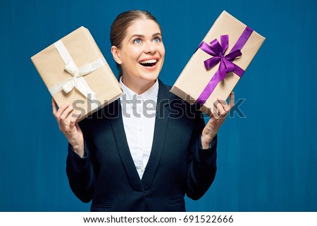 Happy smiling business woman holding gift boxes. Portrait against blue background.
