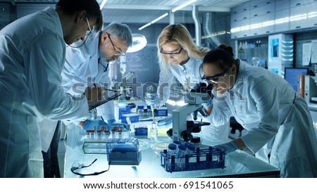 Team of Medical Research Scientists Collectively Working on a New Generation Experimental Drug Treatment. Laboratory Looks Busy, Bright and Modern. Royalty-Free Stock Photo #691541065
