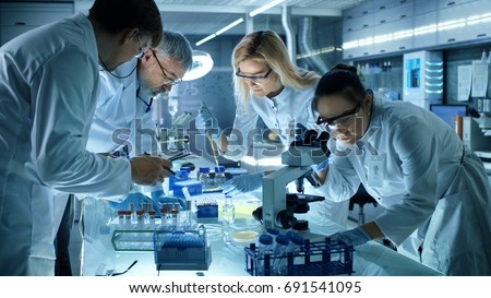 Team of Medical Research Scientists Collectively Working on a New Generation Experimental Drug Treatment. Laboratory Looks Busy, Bright and Modern. Royalty-Free Stock Photo #691541095