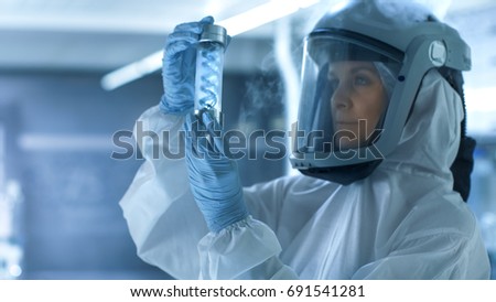 Medical Virology Research Scientist Works in a Hazmat Suit with Mask Smiles in a Cold Environment. She Works in a Sterile High Tech Research Facility. Royalty-Free Stock Photo #691541281