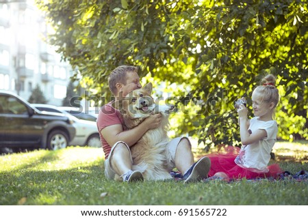 Happy family - little pretty girl with retro camera  taking a picture of father and dog
