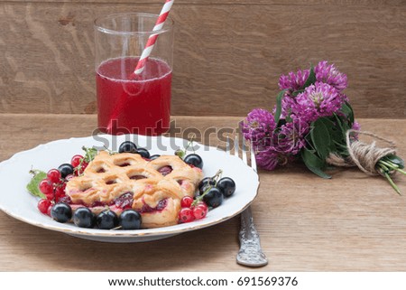 The cake with berry jam is served with red and black currants. Drink
 from red berries. Bouquet of wild flowers of clover.