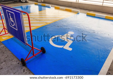 Handicap symbol on road, traffic and pedestrians on parking space