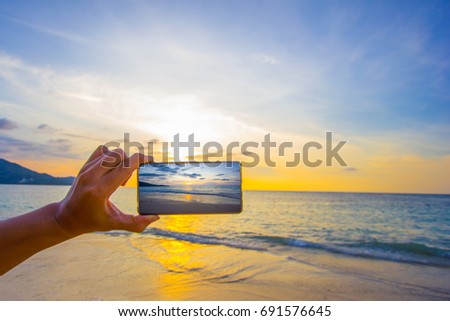 Shooting photo during hand hold mobile and open camera to take the photo at the beach during sunset 