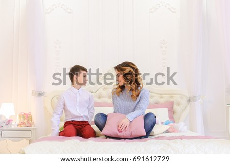 Little boy congratulates mother on new year and gladly presents gift. woman happy, kisses and hugs beloved son with gratitude. Woman with beautiful European hairstyle dressed in blue sweater and dark