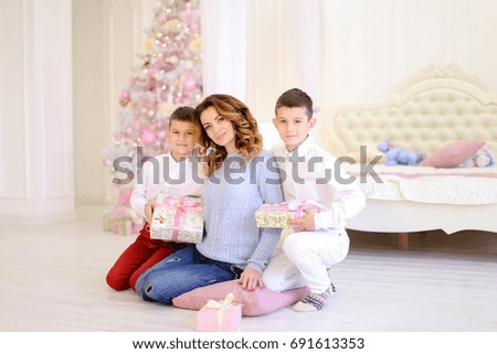 Happy mother and successful woman with children, twin boys spend time together and communicate. Guys give their mothers gifts and woman accepts and gratefully embraces and kisses in family way in pre