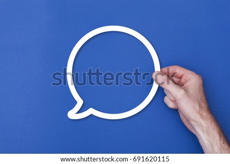 male hand holding a speech bubble icon symbol against a blue background