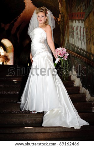 a bride in a gown with a long train on the stairs