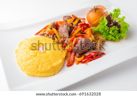 Hominy with vegetable ragout, pieces of beef and pickles on a white plate isolated on white. Restaurant menu. Free space for text. Isolated on white background