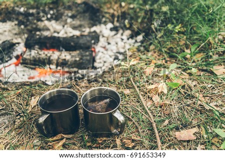camping, two metal cups with tea near bonfire