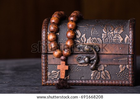 Rosary with a cross in an old box on a wooden background