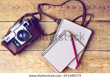 Old retro camera, spiral blank notebook pencil on vintage rustic wooden planks boards. Education photography courses back to  school concept abstract background. Close up, top view.