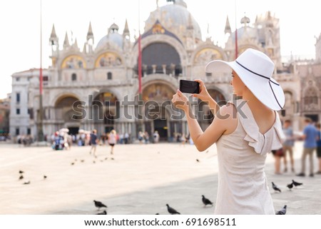 A beautiful young woman taking a pictures in Venice, Italy on Piazza San Marco