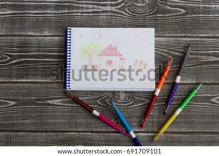 Notebook with children's drawing with pencils on the background of a wooden table