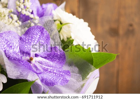 Bouquet of daisy and purple orchid on wooden background with copy space