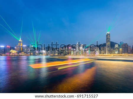 Hong Kong city skyline at dusk with laser show and lights of boat in Victoria harbor