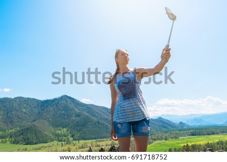 Woman taking selfie on mobile phone with stick. Vacation in the mountain