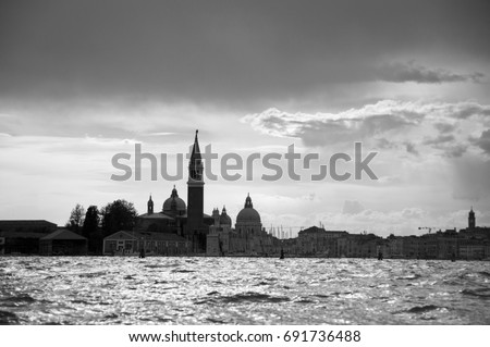 Black and white silhouette of San Giorgio Maggiore in Venice, Italy, Europe. Sunset in Venice, shot from the sea. Gorgeous cloudscape. Photo picture view of the famous Venice Italian city. Cityscape.