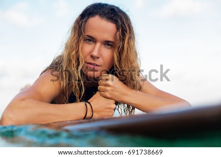 Happy girl in bikini have fun before surfing Surfer lie on surf board, look at sunset sky. People in water sport adventure camp, extreme activity on family summer beach vacation. Watersport background