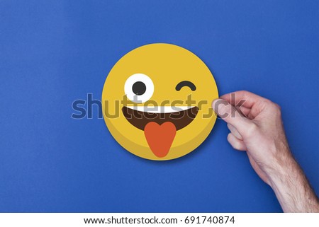 Male hand holding a emoji emoticon smiley head icon