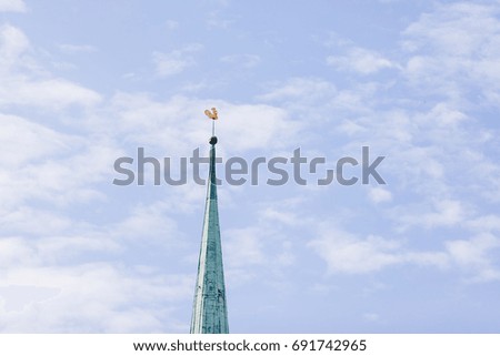 Church tower with golden cock on blue sky background