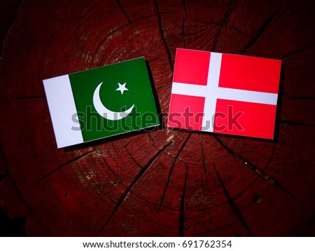 Pakistan flag with Danish flag on a tree stump isolated