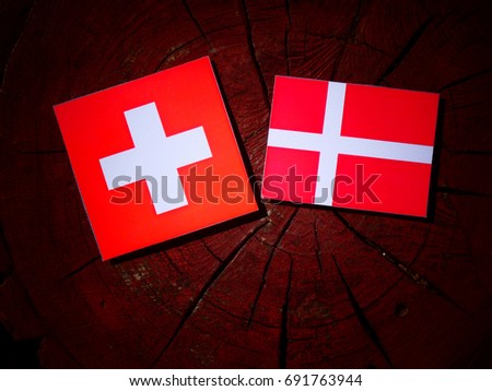 Swiss flag with Danish flag on a tree stump isolated