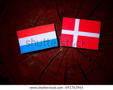 Luxembourg flag with Danish flag on a tree stump isolated