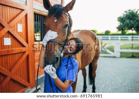 Vet kissing a horse outdoors at ranch.  Royalty-Free Stock Photo #691765981
