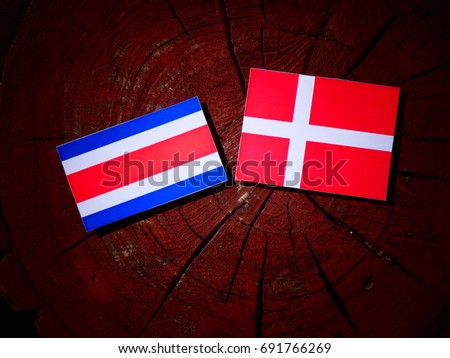 Costa Rican flag with Danish flag on a tree stump isolated