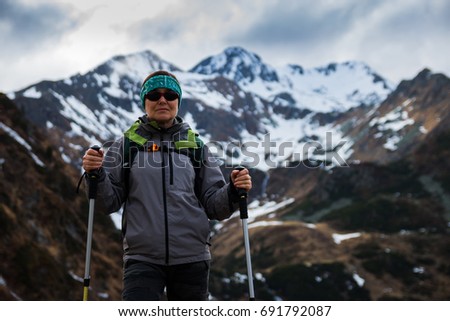 Trekking in mountain. Female tourist on a mountain trail. Mountain hiking equipment with backpack trekking sticks.
