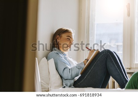 A Beautiful Girl Sitting On The Bed Writing