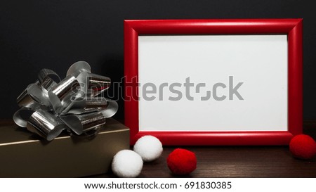 Blank photo red frame on the table with gold gift box with silver ribbons.