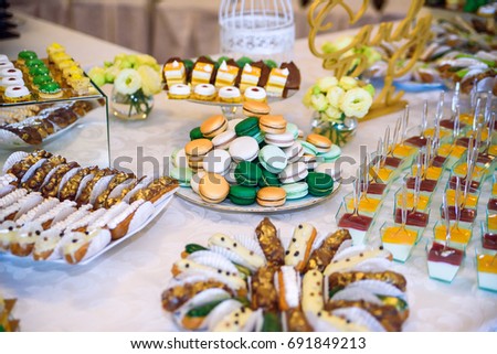 Stylish luxury decorated candy bar for wedding celebration of happy couple, cathering in the restaurant. Delicious wedding reception candy bar dessert table with macaroons.