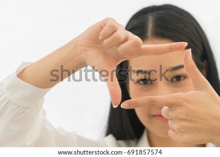 Close up portrait of beautiful asian young woman making frame with her fingers on white background. Focus hand